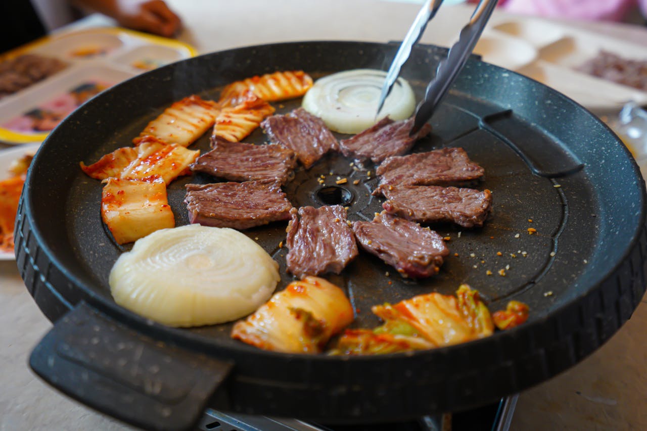 Delicious Korean barbecue featuring beef, onions, and kimchi. Perfect for food lovers.