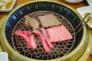 Fresh cuts of meat grilling on a traditional Korean BBQ grill, showcasing culinary delight.